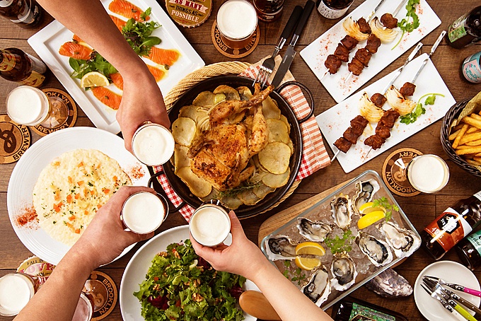 目黒駅西口から徒歩1分、クラフトビール酒場『トリクラヒーロー』の料理をバックに乾杯している画像