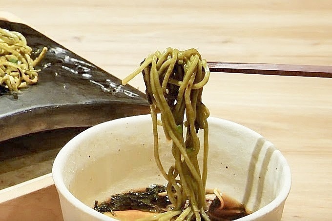 神田にある瓦そば専門店『瓦.Tokyo 神田 Y‐STYLE』の瓦そばをつゆに付けているシーンの画像