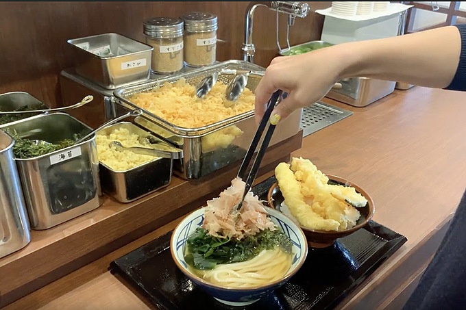 丸亀製麺 JR有楽町駅店 トッピングする様子